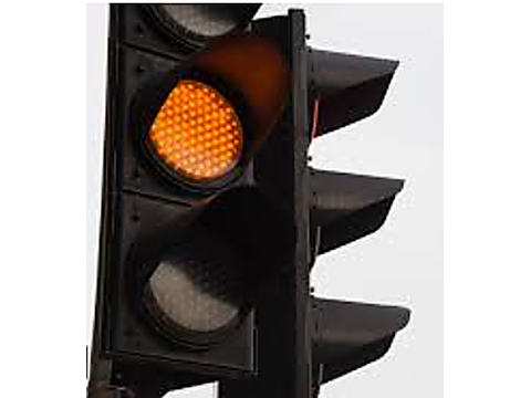 When approaching an intersection where a traffic signal shows a STEADY yellow light: